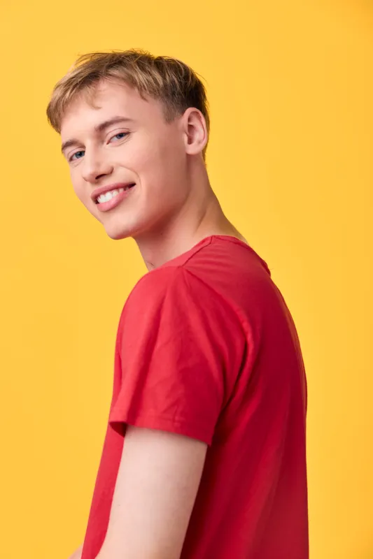 Smile, youth, red shirt, yellow background, casual style, male, friendly expression captured in a bright studio setting, showcasing a modern, approachable vibe ideal for lifestyle and fashion themes