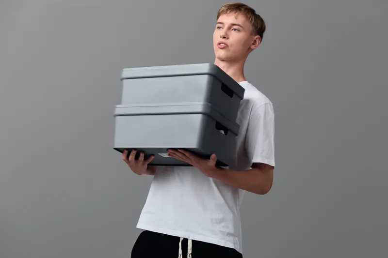 Man holding stacked delivery boxes in a warehouse setting, highlighting packaging, logistics and shipment readiness for ecommerce fulfillment