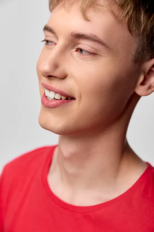 Smiling man in a red shirt with a joyful expression, casual style, and bright mood, captured in natural light for lifestyle, cheerful vibe, and approachable visuals