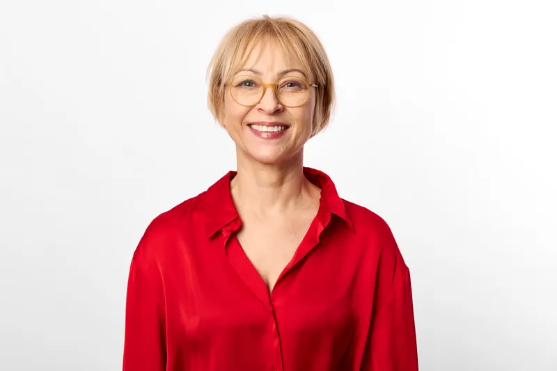 Woman, smile, glasses, red blouse, senior portrait, studio white background beauty, soft lighting, warm face expression, friendly confidence, elegant clothing