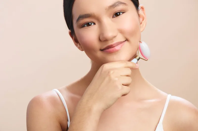 Asian woman portrait in a studio setting, poised and confident, showcasing soft lighting and natural makeup. A serene expression highlights clear complexion and professional charm.