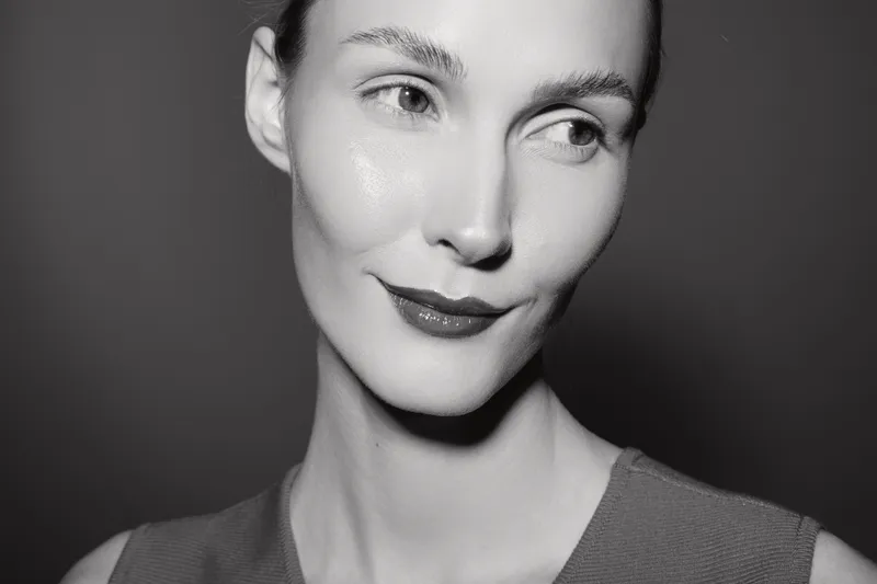 Close-up portrait of a young caucasian woman with fair skin and short hair looking aside with subtle smile in studio lighting. Concept of beauty and natural elegance.