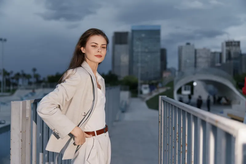 Confident businesswoman in smart attire against a modern cityscape, showcasing elegance and determination in a professional setting.