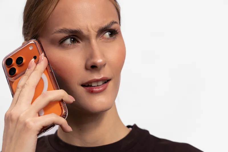 Young woman with serious expression holding smartphone to ear, looking sideways. Concept of communication, technology, and focused conversation in modern life.