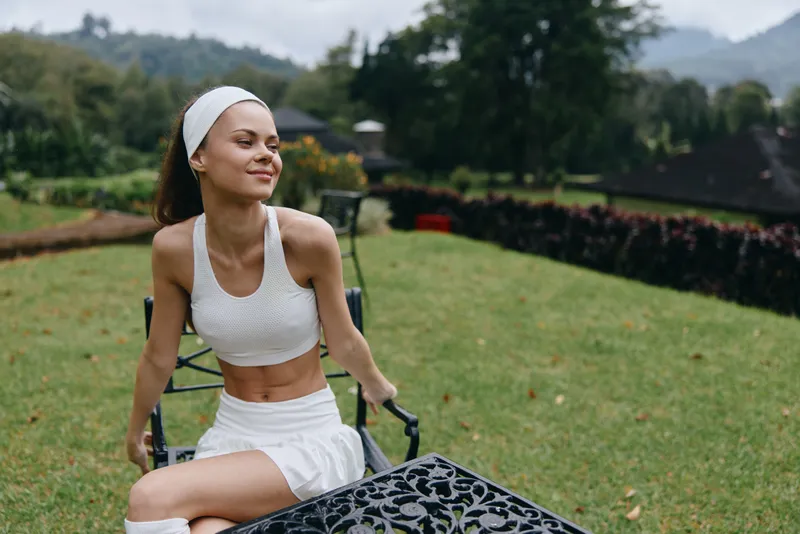 Young woman enjoying the outdoors in sporty attire, exuding confidence and happiness in a serene garden setting, perfect for wellness and active lifestyle contexts