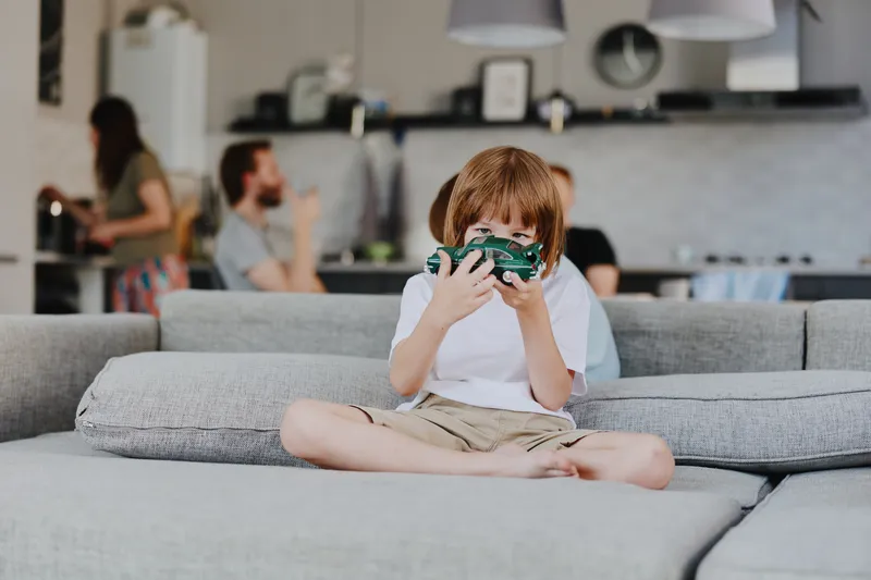 Happy boy playing with a toy car in a cozy living room, enjoying quality time with family in a modern, relaxed atmosphere.