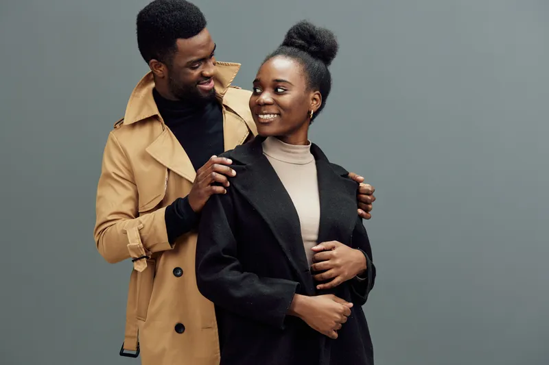 Happy couple in stylish outfits, with a light gray backdrop, representing love, confidence, and modern fashion trends