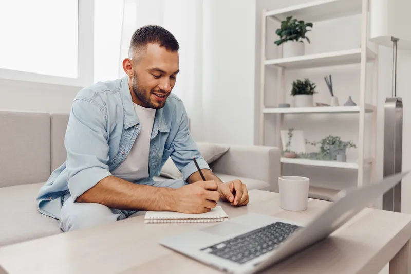 A focused man writing in a notebook, reflecting on his career pivoting and emotional minimalism while embracing the mindfulness of solo living and soft masculinity.