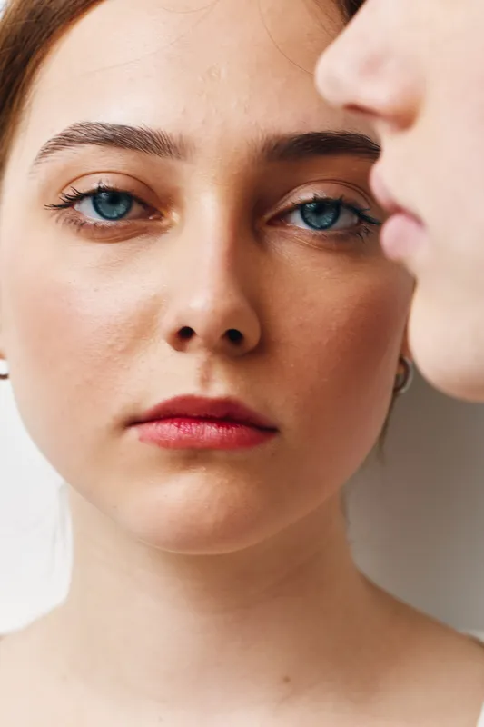Women, closeup and faces with serious expression and natural makeup for beauty, emotion and portrait photography. Female models with blue eyes and soft skin in studio with white background.
