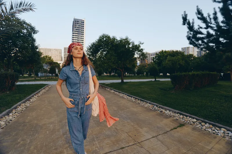 Lifestyle woman in modern boho-western denim street style walking confidently outdoors with film color effect during golden hour.