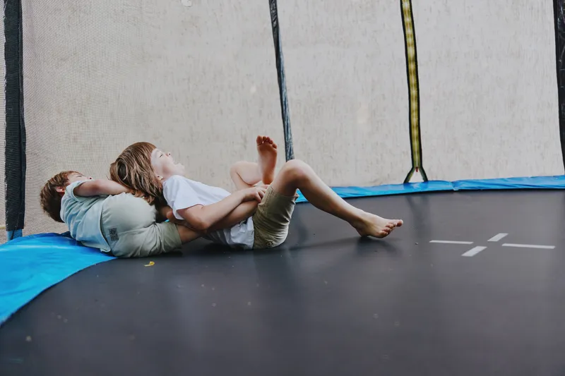 Two playful children enjoying a fun moment on a trampoline, showcasing joy, laughter, and carefree childhood emotions.