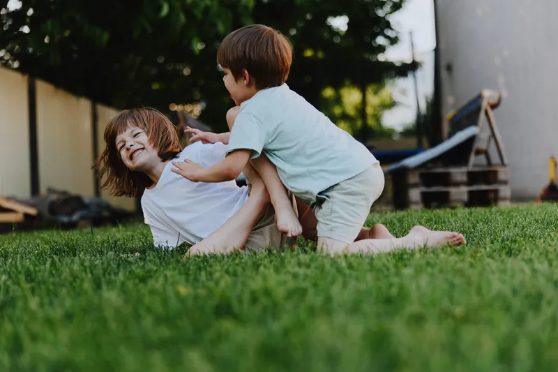 Happy children playing together on a grassy lawn, enjoying the sunlight and bonding through laughter and fun. Perfect for portraying childhood joy and friendship.