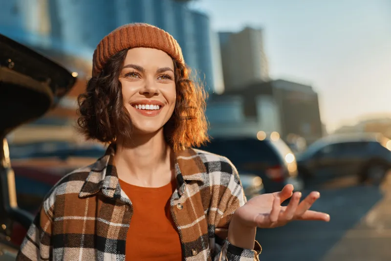 Woman smile beanie urban city sunlight portrait happiness captured in candid lifestyle shot with authenticity and golden hour glow, mindful living vibe and emotional storytelling in street scene