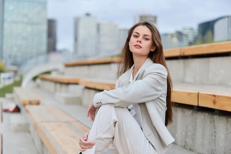 Confident businesswoman in stylish outfit seated outdoors, exuding professionalism and focus in an urban setting, ideal for corporate imagery and modern concepts.