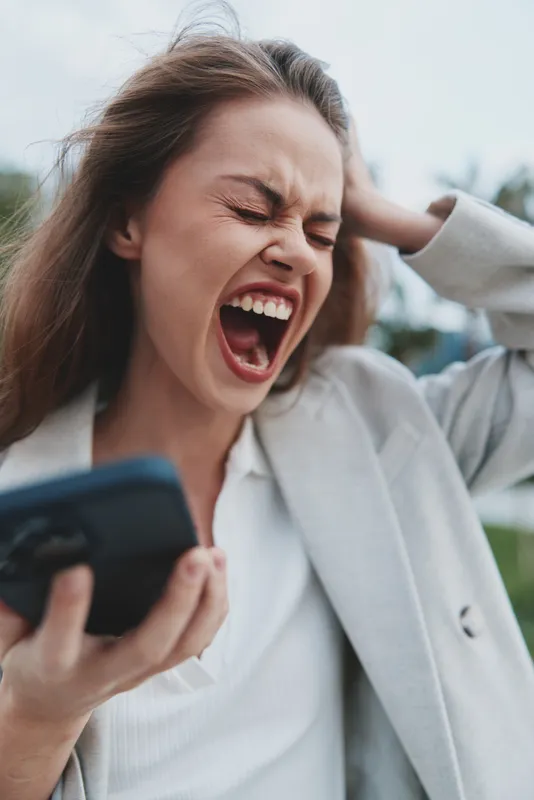 Frustrated woman in business attire shouting holding phone expressing stress financial crisis fall stocks emotional face