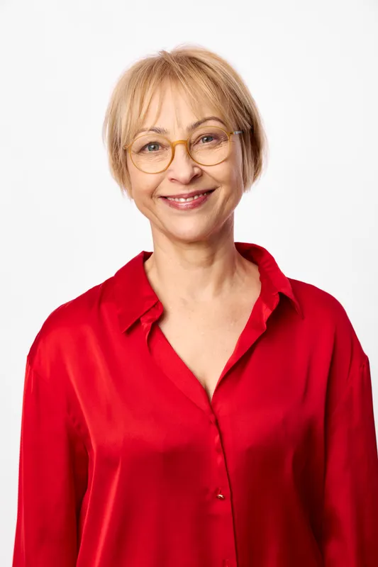 Smiling senior woman with glasses, red blouse, studio portrait on white background, friendly relaxed look, short hair, isolated headshot, calm positive mood