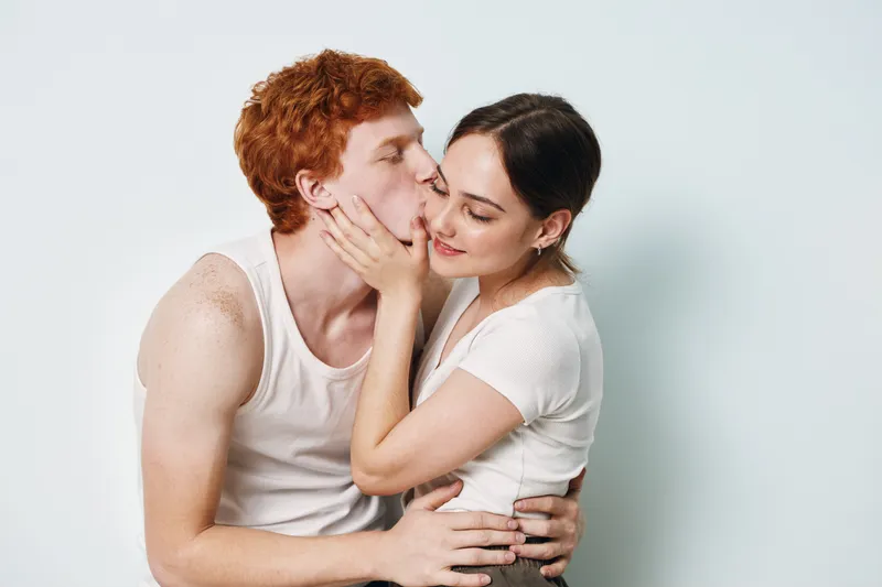 Couple, love, romance, kiss, intimacy, affection, relationship, young, tenderness, togetherness, emotional connection and happiness between man and woman in casual clothes on white background.