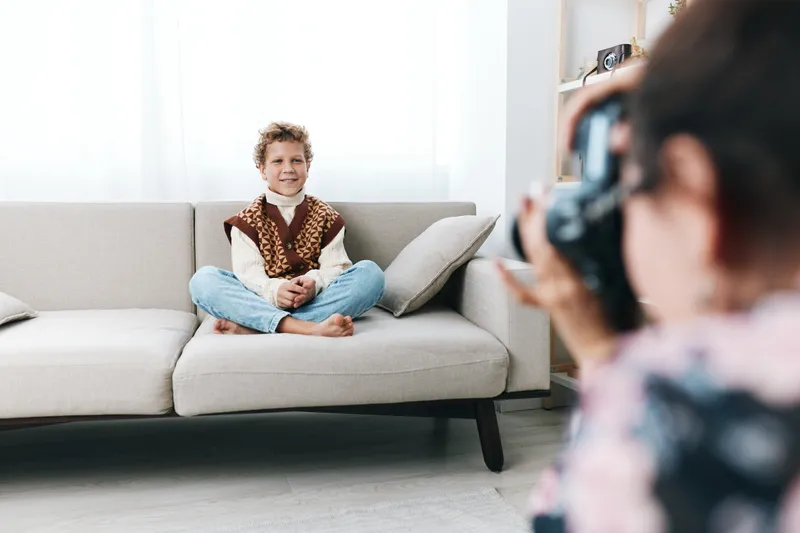 Authentic lifestyle photography capturing a child at home in a playful school themed moment, seated on a couch, relaxed pose, natural light, everyday learning vibe.