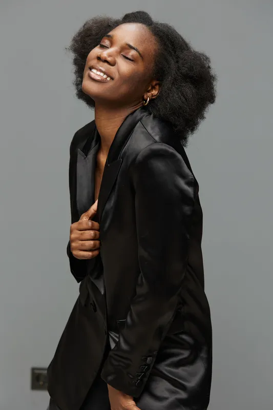 Elegant Black Woman Smiling in Stylish Black Suit Pose for Contemporary Fashion Concept