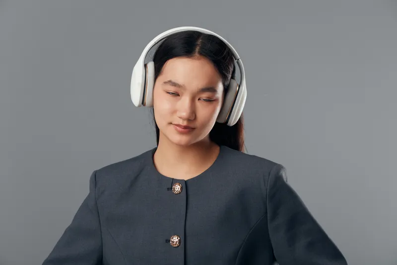 Woman with headphones enjoying music with closed eyes on gray background in studio. Female person listening song with relaxation, calm expression and dark hair for lifestyle concept.