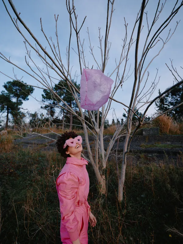 Pink dress worn by a woman in an outdoor scene with bare trees and a floating pink lantern, capturing a whimsical moment in a natural landscape.