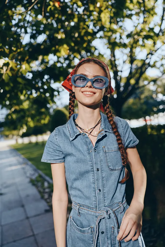 modern boho-western denim street style woman smiling outdoors with sunglasses and braids, film color natural light urban background summer fashion
