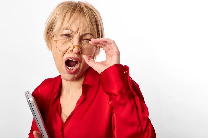 Stressed woman doctor in red medical uniform coughs with hand over mouth, eyes closed, isolated on white background, concept for respiratory illness