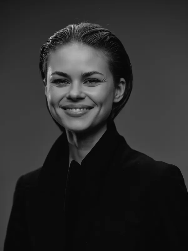 Smiling woman in black coat with slicked-back hair, monochrome portrait expressing confidence and elegance