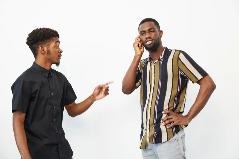Two African American men engaged in a conversation, illustrating friendship and communication in a modern setting. Their expressions convey a blend of curiosity and understanding.
