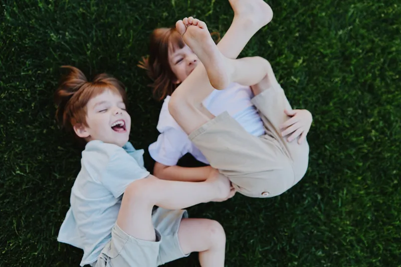 Happy children playing together on green grass, sharing laughter and joy, capturing the essence of childhood. Enjoy the vibrant summer vibes in this playful scene.