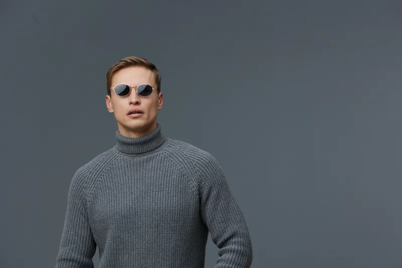 young man wearing sunglasses gray knitted turtleneck sweater posing serious isolated on gray background casual fashion style digital nomad concept