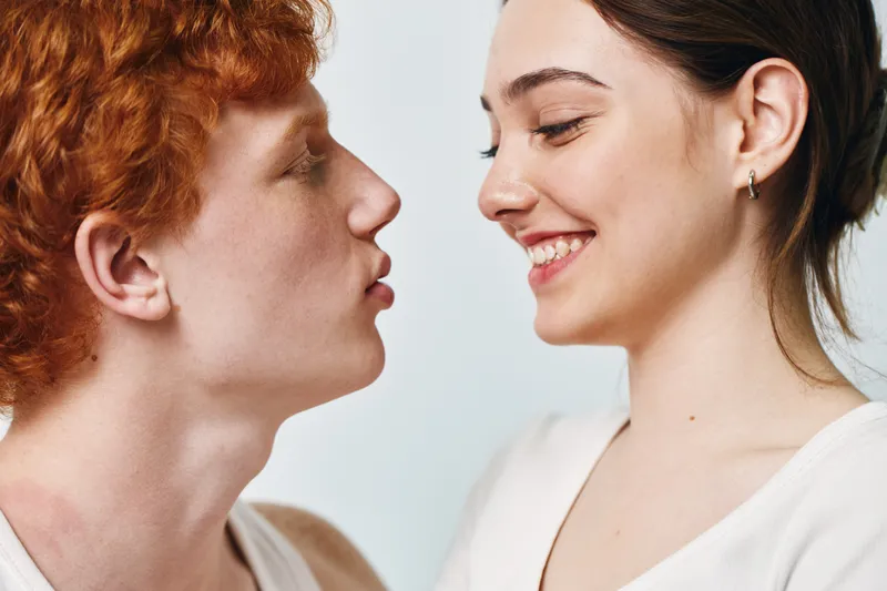 Young man and woman close face to face smiling for lifestyle, friendship, affection and relationship in love and happiness with casual clothes on white background.