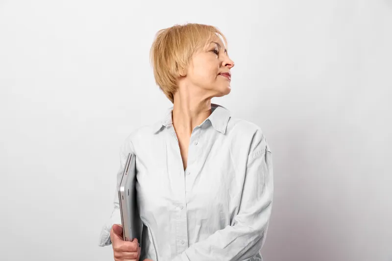 Elderly woman doctor in white coat holding stethoscope in side profile, healthcare and medicine concept, soft studio lighting, calm clinical mood