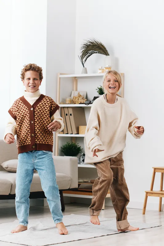 Authentic scene of children at home engaging in playful movement, capturing school inspired activity and genuine youth energy in a cozy, comfortable setting. The composition emphasizes authenticity,