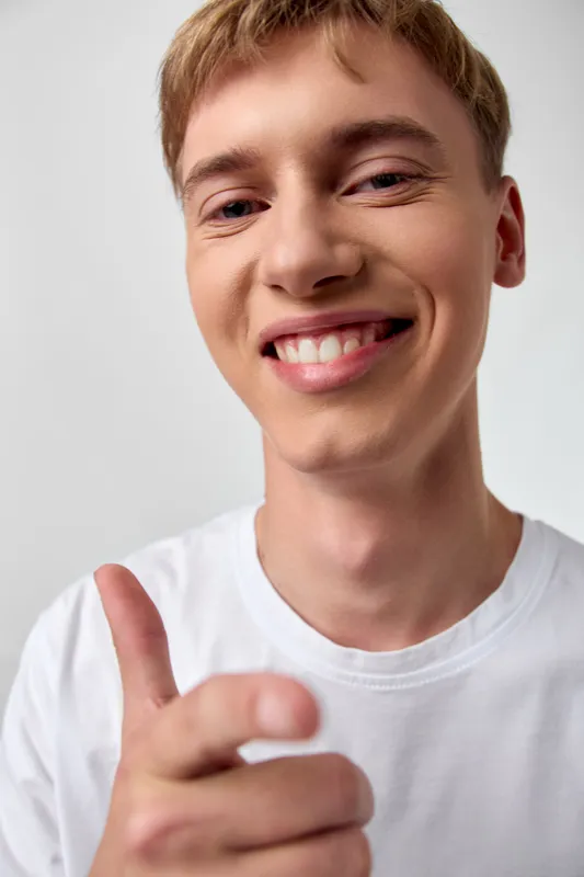 Smiling man with a thumbsup gesture in closeup shot, conveying happiness and confidence. Casual vibe, youthful energy, friendly expression, bright light, inviting and approachable mood for lifestyle