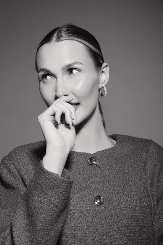 Young caucasian woman with fair skin and blonde hair poses thoughtfully wearing a textured sweater in a monochrome studio portrait concept of contemplation.