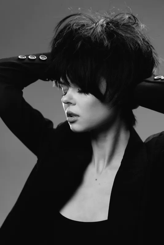 Black and white portrait of thoughtful woman with short hair in dark blazer expressing emotion