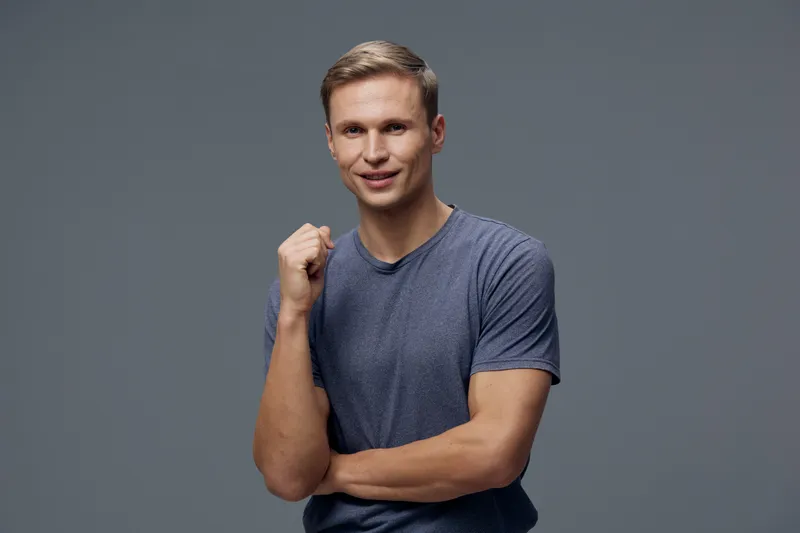 smiling caucasian man wear casual t-shirt look camera show fist gesture isolated on gray background digital nomad freelance concept