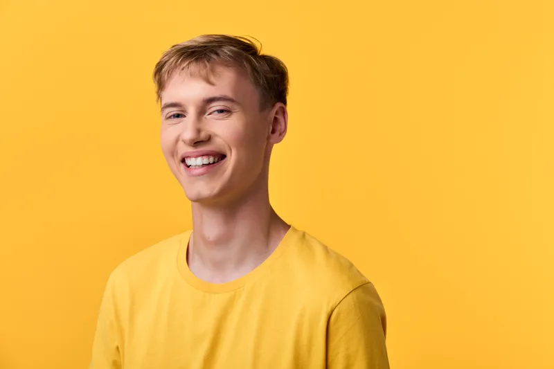 Smile filled image of a man in a yellow shirt against a bright yellow background, conveying happiness, casual style, and positive energy for lifestyle and commercial use