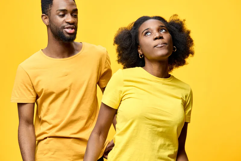 Young couple in matching yellow outfits, showcasing playful emotions against a vibrant yellow background, perfect for friendship and love themes