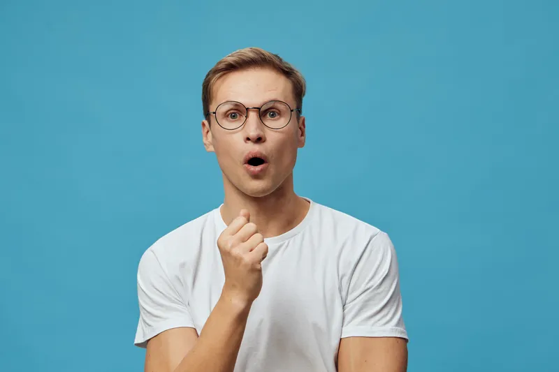 surprised young caucasian man glasses white t-shirt open mouth isolated blue background digital detox concept