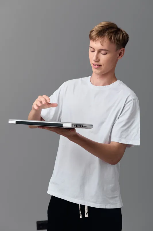 Tablet technology interaction by a young man in a white shirt presenting on screen content with a focused gesture in a studio setting