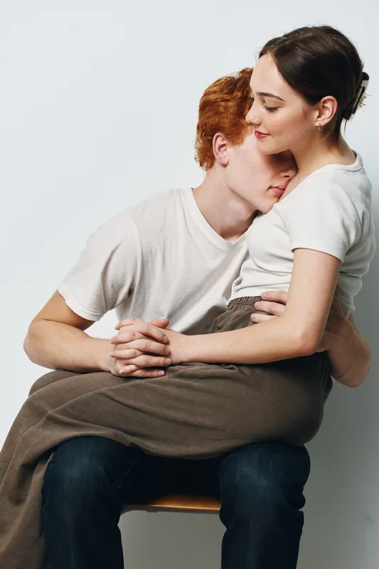 Couple, love, hug, and affection with young man hugging woman sitting on lap for relationship, intimacy, comfort, and tenderness in studio. Emotions, trust, and closeness between two people.