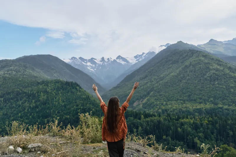 Person woman mountains nature hiking freedom with arms raised at peak, outdoor exploration and authentic inclusivity in wilderness