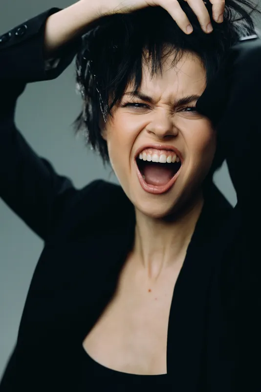 expressive woman shouting with messy hair in dark blazer showing strong emotion