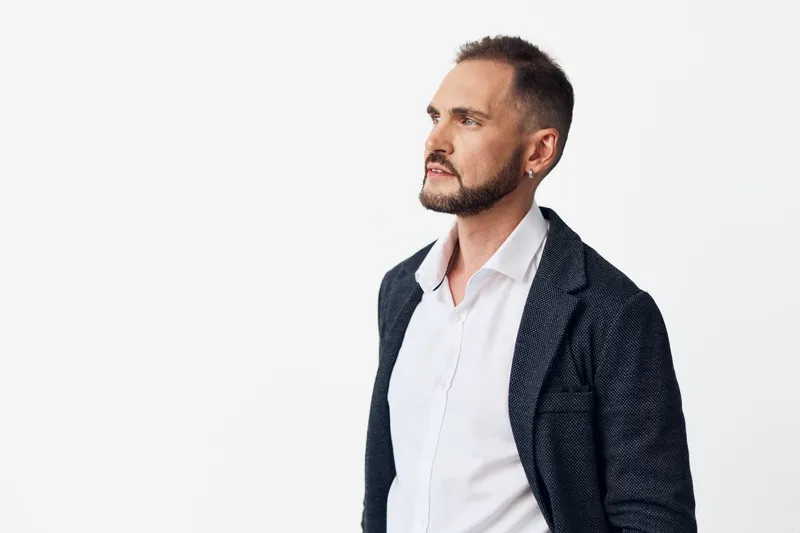 A professional man stands against an isolated colored background, exuding confidence and focus. The clean setup highlights business expertise and calm determination.