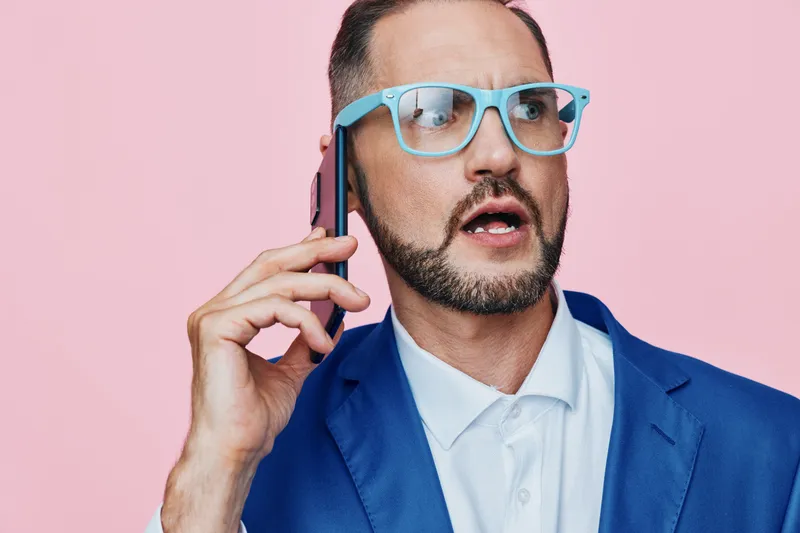 Professional man on a business call stands against an isolated colored background, projecting confident, anxious, and focused emotions as he negotiates a deal and communicates clearly.