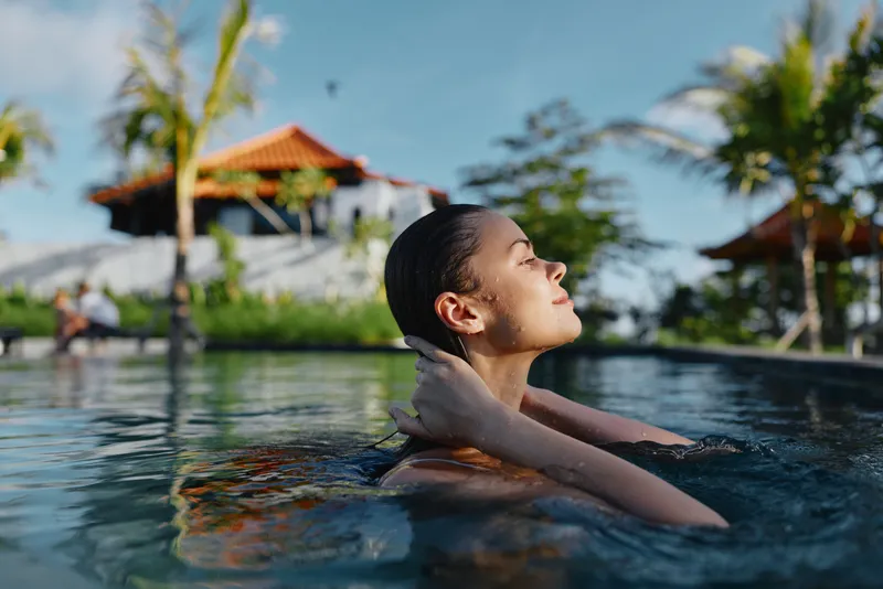 Pool woman swimming relaxation vacation tropical resort outdoor leisure water a calm close scene of a woman in a pool with head tilted back enjoying warm light and a tranquil mood