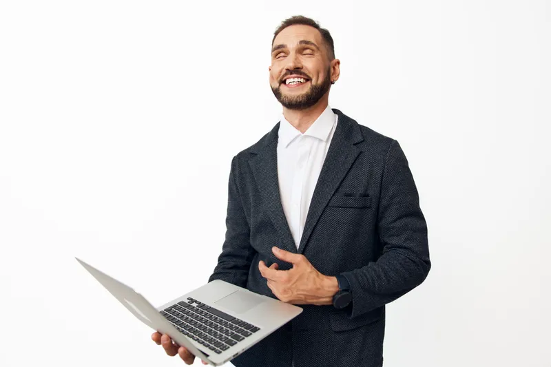Business professional man on an isolated colored background, smiling with confidence while presenting a laptop, conveying motivation, energy, and approachable leadership.
