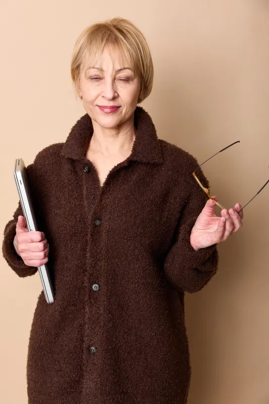 Elderly woman portrait in studio, beige background, holding tablet with stylus, calm mature mood, shows technology learning for online browsing, independence and wellness
